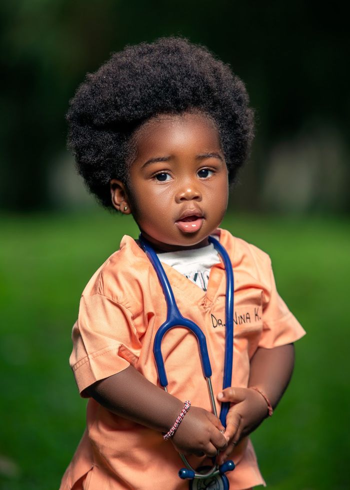 Cute African toddler dressed as a doctor with stethoscope, outdoors in Aburi, Ghana.