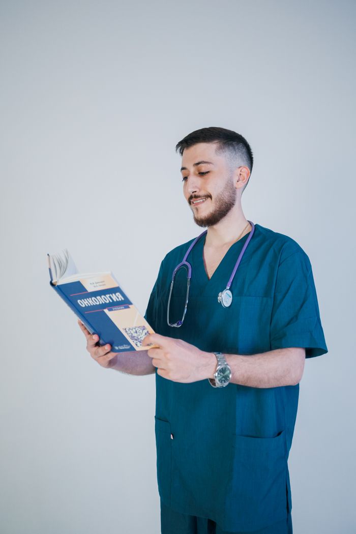 The Art of Drawing Readers In: Your attractive post title goes here Young male nurse reading an oncology book in scrubs with a stethoscope in a bright setting.